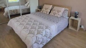 Ein Schlafzimmer mit einem großen Bett, einem Nachttisch, einem Spiegel und einer Hängeleuchte.