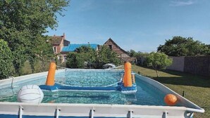 Ein aufblasbarer Pool mit zwei orangen Stangen, einem Volleyball und einem orangen Ball.