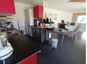 Uma cozinha moderna com bancada preta, eletrodomésticos de aço inoxidável e um armário vermelho.