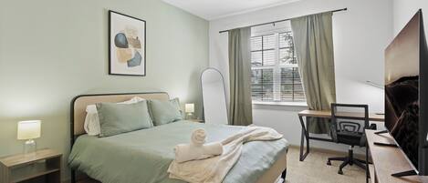 Un dormitorio ordenado con cama, mesitas de noche, escritorio y silla.