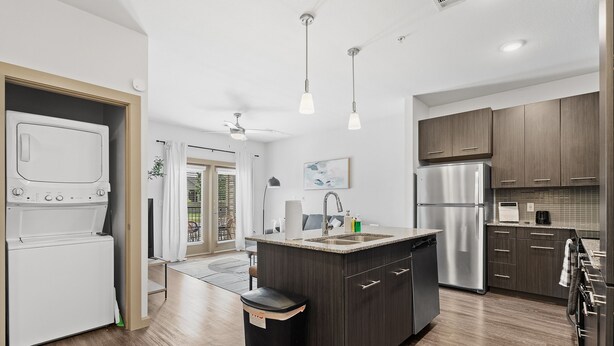 A modern kitchen with a central island, stainless steel appliances, and dark wood cabinetry. - Luxe 2B Getaway | Sleeps 6 | Pool, Gym, Garage (Leander)