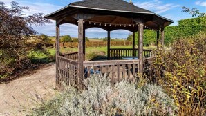 A wooden gazebo with a sloped roof, surrounded by vegetation and a dirt path. - Anjou - Manoir Les Touches (Doué-en-Anjou)