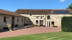 A stone building with a tiled roof, a paved driveway, and potted plants. - Anjou - Manoir Les Touches (Doué-en-Anjou)