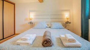 A neatly made bed with pillows, two bedside lamps, and rolled towels on a patterned bedspread. - Anjou - Manoir Les Touches (Doué-en-Anjou)