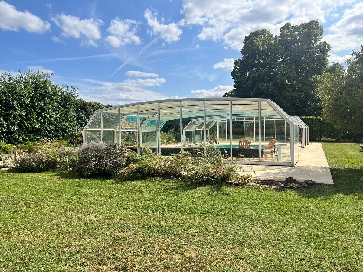 A glass-enclosed structure with a pool and seating area.