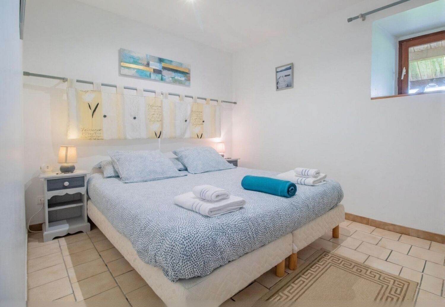 Quarto bem organizado com cama, mesas de cabeceira e uma janela.
