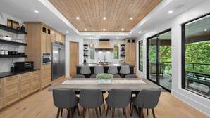 A modern kitchen with wooden cabinets, a central island, and a dining area with four chairs.
