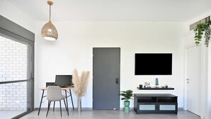 Et moderne værelse med skrivebord, stol og et ophængt TV.
