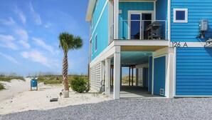A two-story building with a blue exterior, a balcony on the upper floor, and a covered entrance. - Modern Coastal Design ~ Sea La Vie (Mexico Beach)