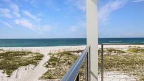 A beach view from a balcony with a clear sky and ocean in the background. - Modern Coastal Design ~ Sea La Vie (Mexico Beach)