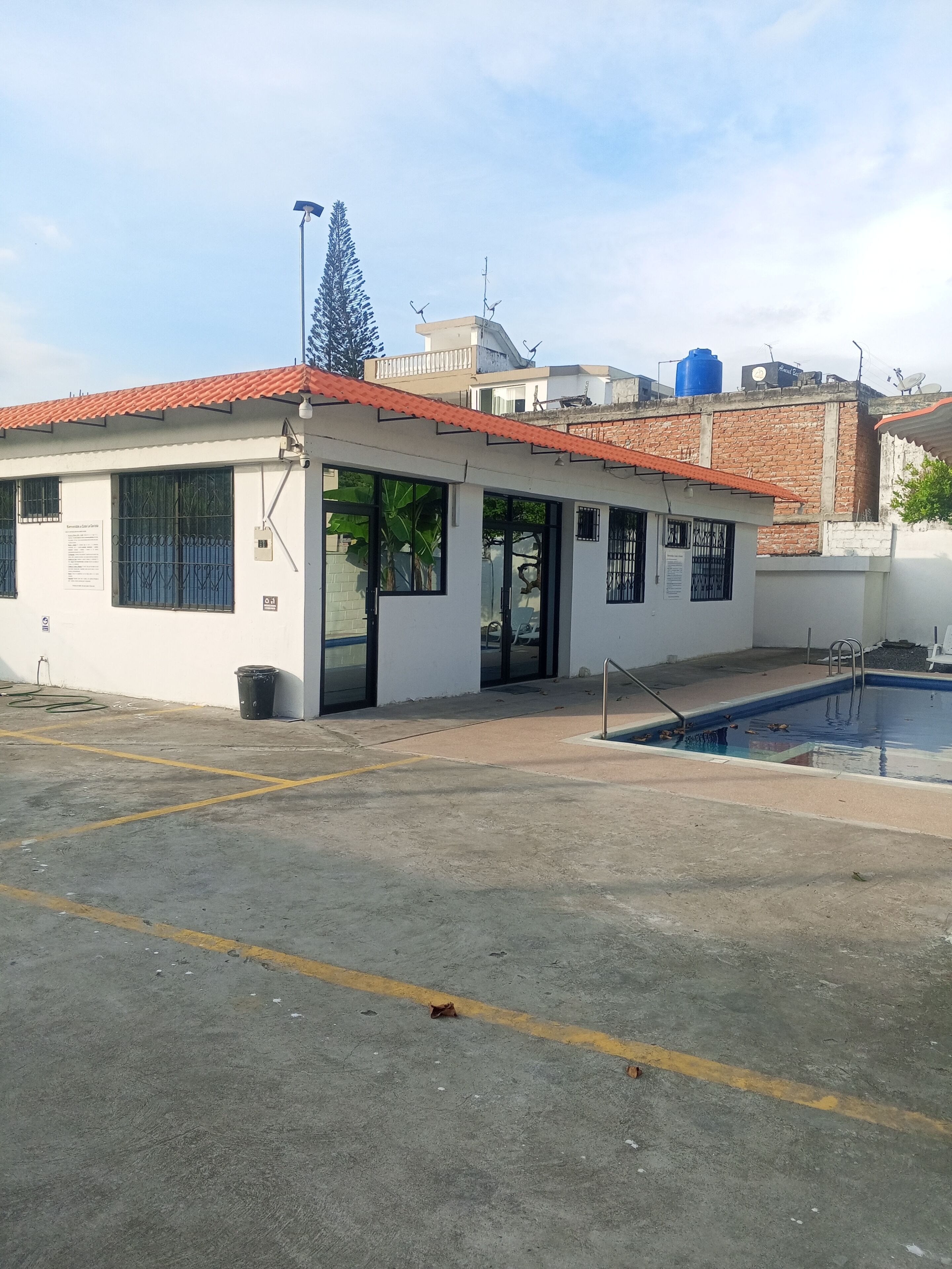 A building with a red-tiled roof, a swimming pool, and a covered outdoor area.