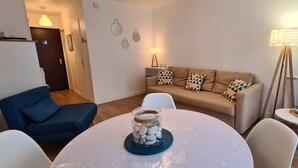 A modern living room with a sofa, chairs, a coffee table with a decorative jar, and a floor lamp.