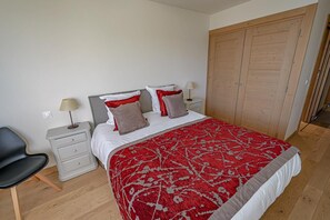 A bedroom with a bed, nightstands, a chair, and a wardrobe. - 50m from ski slopes, fitness, swimming pool, sauna, hammam, terrace, ski locker, 75m², Les Arcs (Bourg-Saint-Maurice)