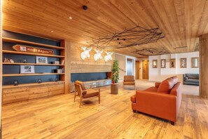 Un hall d’hôtel spacieux, doté d’un plancher en bois, d’un comptoir de réception et d’un espace détente avec un canapé et des fauteuils.