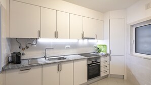 A modern kitchen with white cabinets, a stainless steel sink, and a built-in oven.
