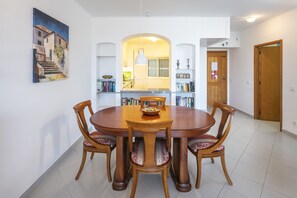 Uma sala de jantar com uma mesa redonda de madeira, seis cadeiras e um quadro na parede.