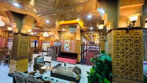 A spacious lobby with wooden ceiling beams, a central seating area with a red sofa, and a decorative fountain. - Hotel shimla hills international (Theog)