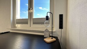 A desk with a lamp, a remote control, and a wall socket. - B&W Apartments - DG Wohnung (Morschen)