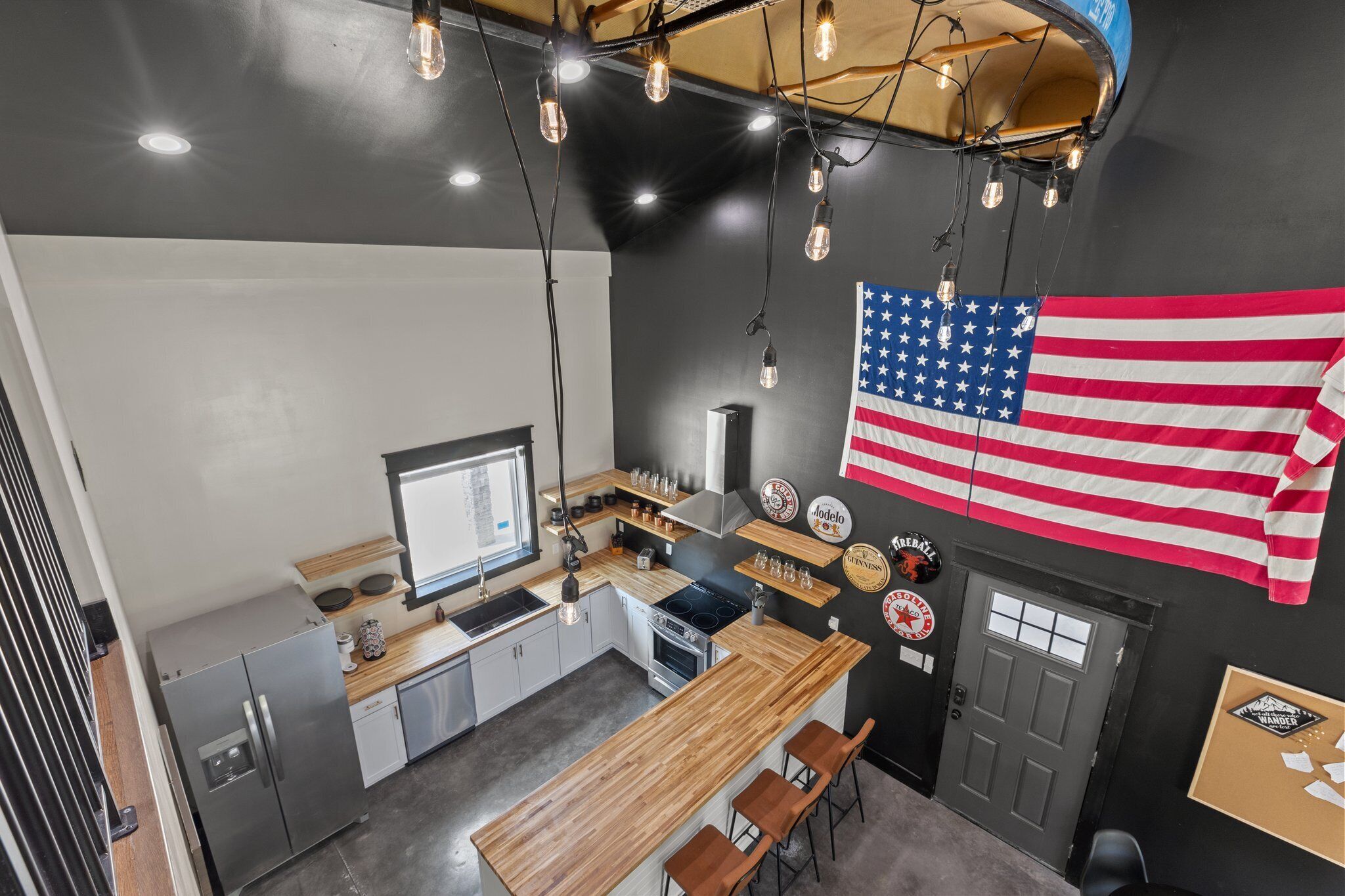 A modern kitchen with a wooden countertop, stainless steel appliances, and a large American flag.