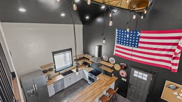 Une cuisine moderne avec un plan de travail en bois, des appareils électroménagers en acier inoxydable et un grand drapeau américain.