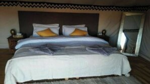 Un dormitorio con cama, almohadas, una mesita de noche y un espejo.