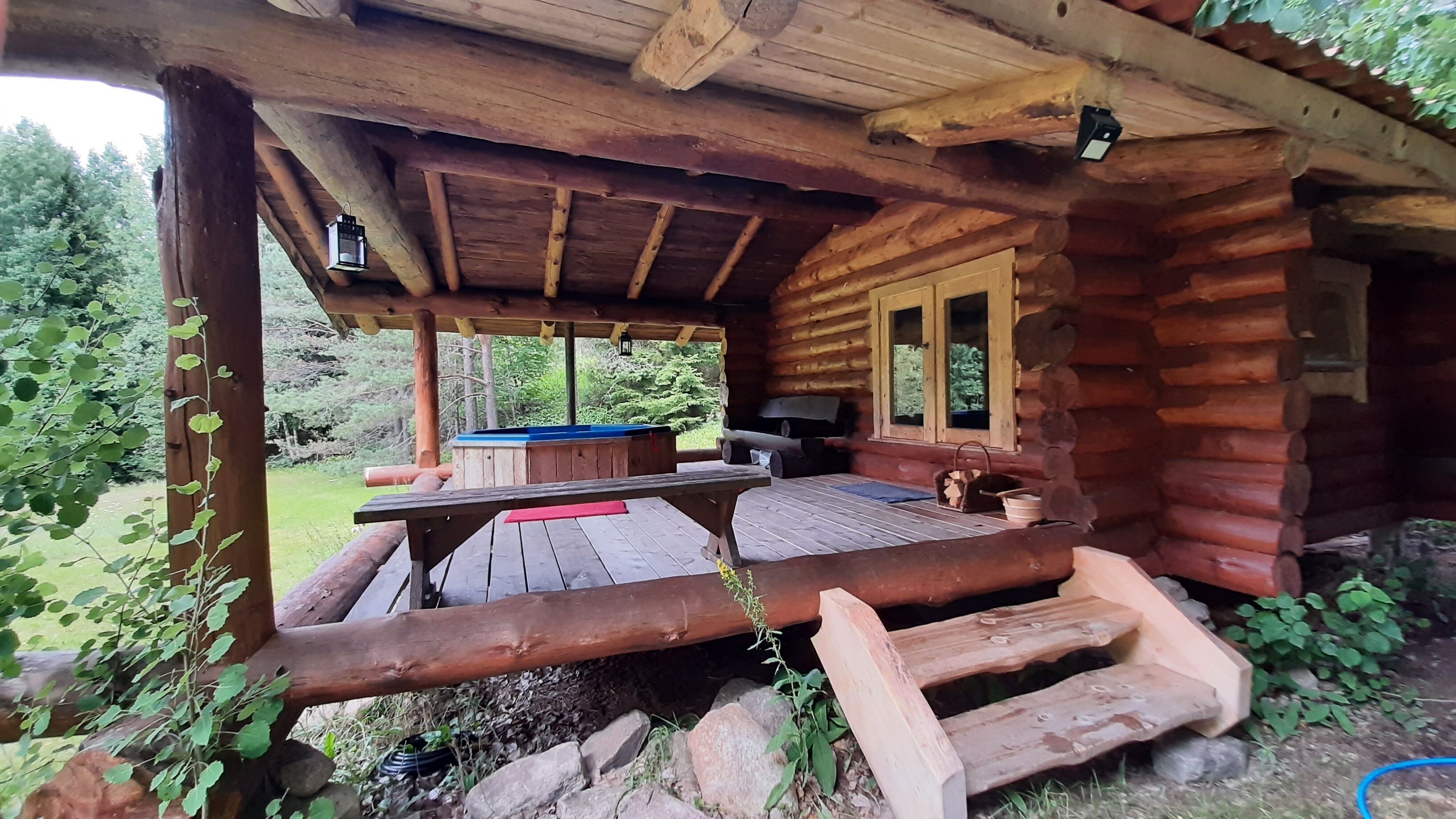 A rustic wooden cabin with a covered patio area, a pool table, and a seating area with a table and chairs.