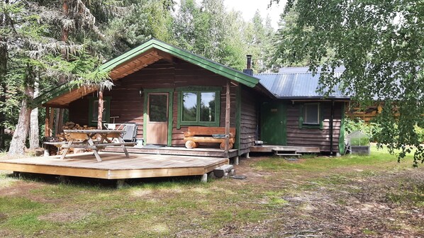 A cabin with a wooden deck, a covered seating area, and a small garden area.