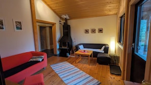 Ein gemütliches Wohnzimmer mit einem roten Sofa, einem schwarzen Sofa, einem Holztisch und einem Kamin.