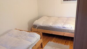 A small, cozy room with two wooden bunk beds, a wooden ceiling, and a framed picture on the wall. - Vacation home with lake view, log cabin sauna and jacuzzi (Lakene)