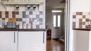 Een keuken met een broodrooster, theezeef en koffie, en een plank met glazen.