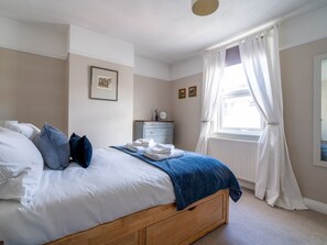 Cozy retreat with a comfortable bed, dresser, and large window.