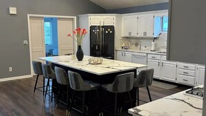 A modern kitchen with a central island, white cabinets, and a black refrigerator. - Fully renovated modern beach home in Orltey Beach
 (Seaside Heights)