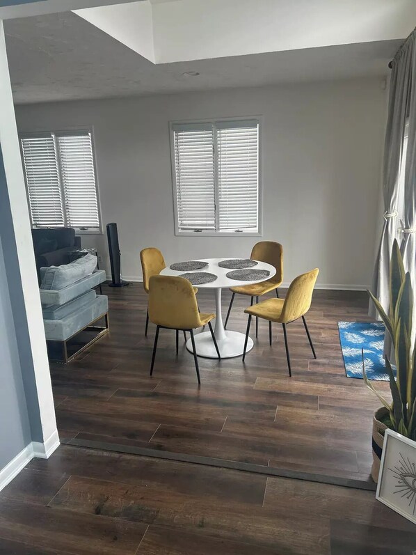 Un comedor con una mesa redonda y cuatro sillas, un sofá y un televisor en una sala de estar.