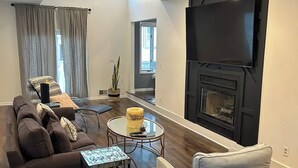 A modern living room with a sofa, armchair, coffee table, and a flat-screen TV mounted on the wall. - Fully renovated modern beach home in Orltey Beach
 (Seaside Heights)