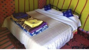 Een bed met een beddegoed met patroon, kussens en een opgevouwen deken.