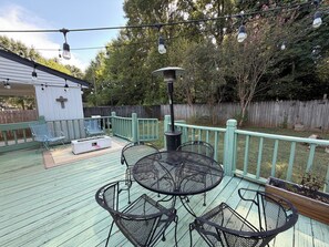 An outdoor deck with metal chairs and a table, surrounded by a wooden fence and trees. - 3 Bed, 1 Bath Adorable Home – Less than 10 minutes from Bryant-Denny Stadium! (Northport)