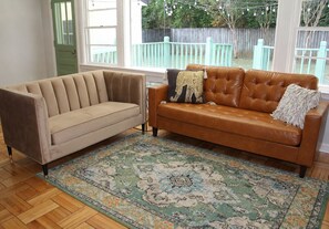 A room with a beige sofa, a brown leather sofa, and a patterned rug. - 3 Bed, 1 Bath Adorable Home – Less than 10 minutes from Bryant-Denny Stadium! (Northport)