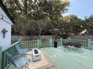 A deck with outdoor furniture, a fire pit, and string lights.