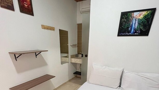 A bedroom with a bed, a brown blanket, a white pillow, a white pillow, a white pillow, a white pillow, a white pillow, a white pillow, a white pillow, a white pillow, a white pillow, a white pillow, a white pillow, a white pillow, a white pillow, a white pillow, a white pillow, a white pillow, a white pillow, a white pillow, a white pillow, a white pillow, a white pillow, a white pillow, a white pillow, a white pillow, a white pillow, a white pillow, a white pillow, a white pillow, a white pillow, a white pillow, a white pillow, a white pillow, a white pillow, a white pillow, a white pillow, a white pillow, a white pillow, a white pillow, a white pillow, a white pillow, a white pillow, a white pillow, a white pillow, a white pillow, a white pillow, a white pillow, a white pillow - Pousada Raízes (Alto Paraíso de Goiás)