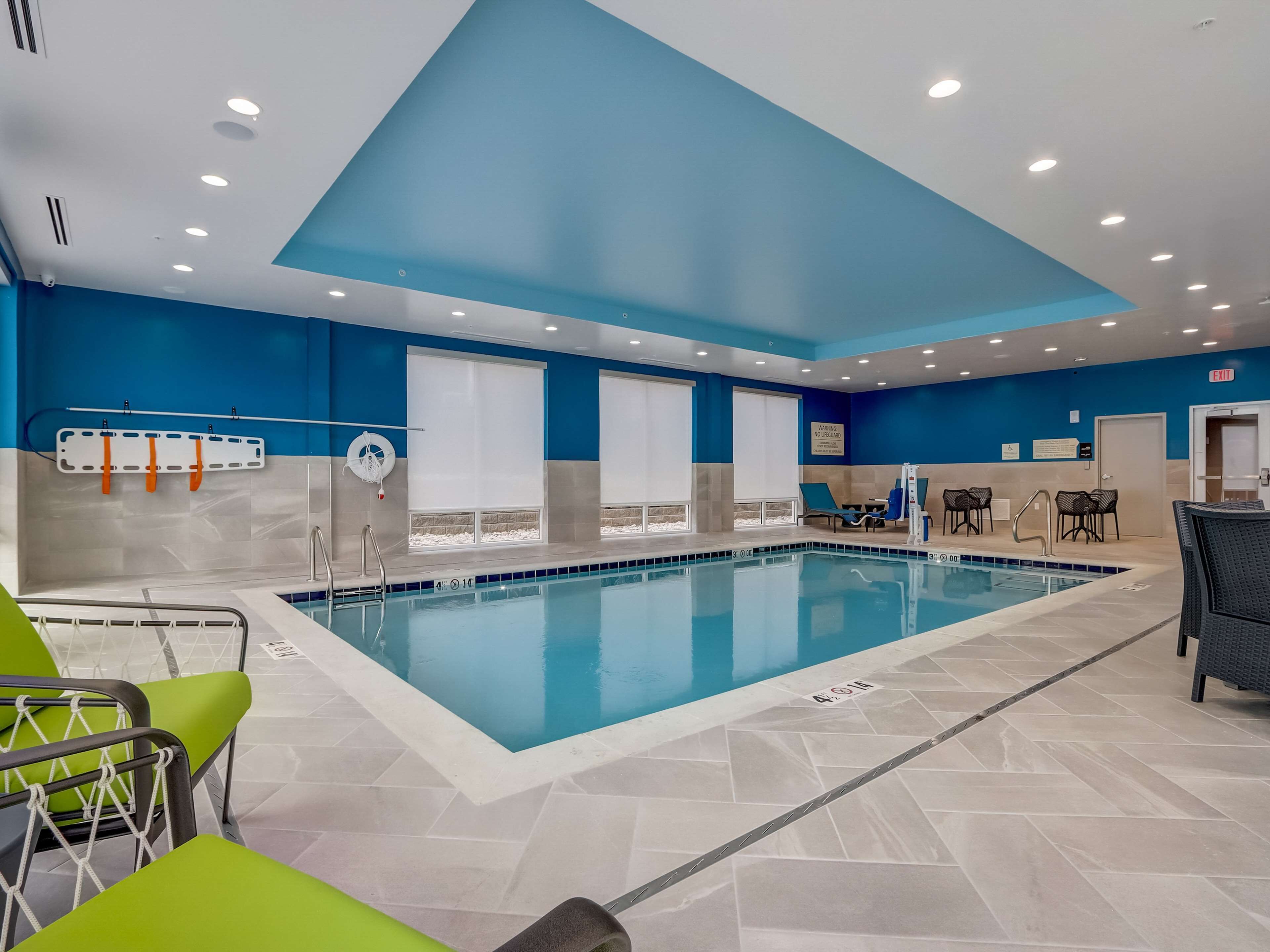 Una piscina interior con agua cristalina, rodeada de paredes azules y suelo de baldosas.