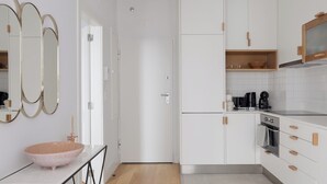 A modern kitchen with white cabinets, a wooden countertop, and a large mirror. - Romantic Gem in Santa Catarina (Lisboa)