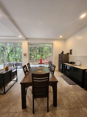 Enjoy meals in this dining area with a large table and comfortable seating, surrounded by a beautiful outdoor view.