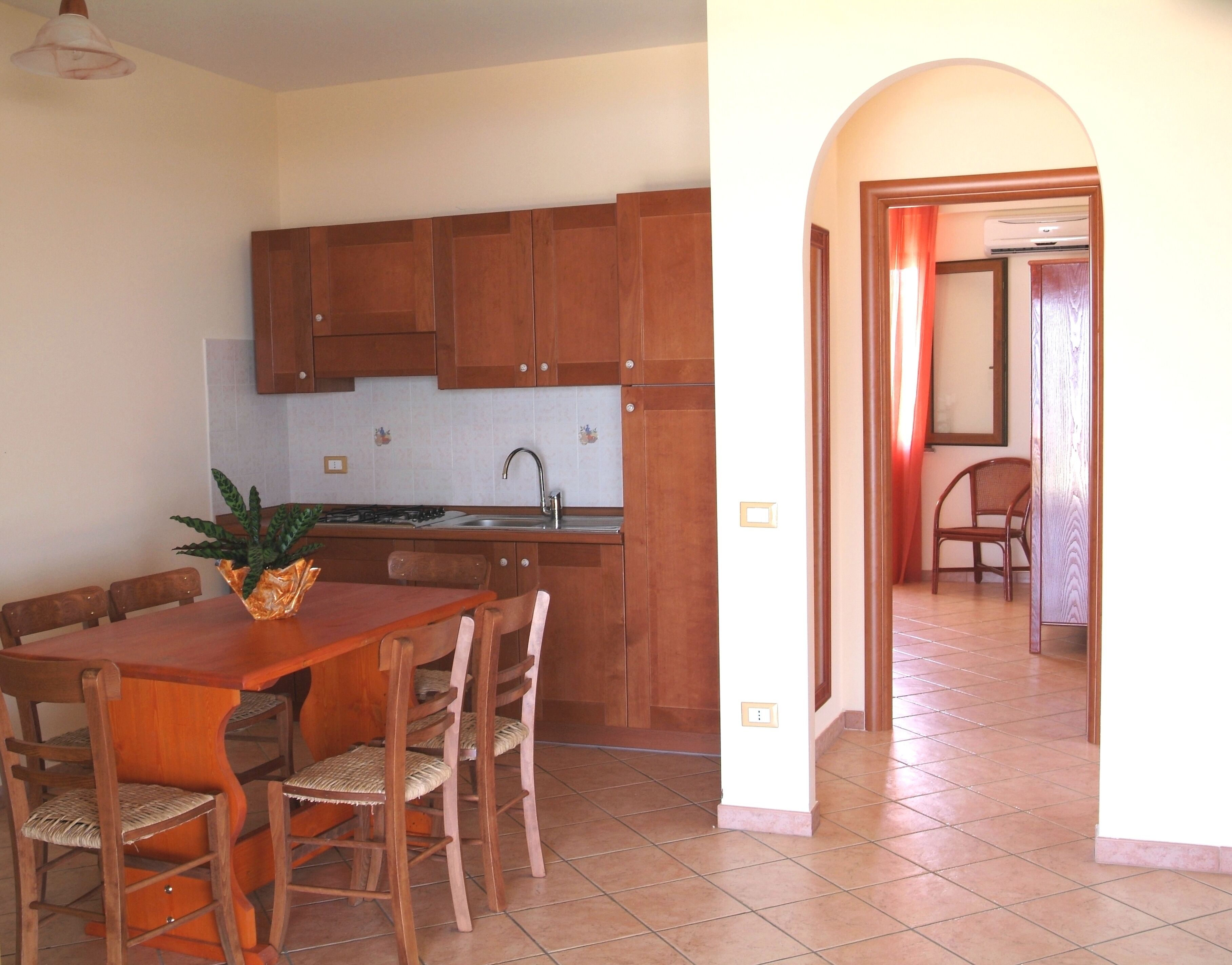 A kitchen with wooden cabinets, a tiled backsplash, and a dining area with a wooden table and chairs.