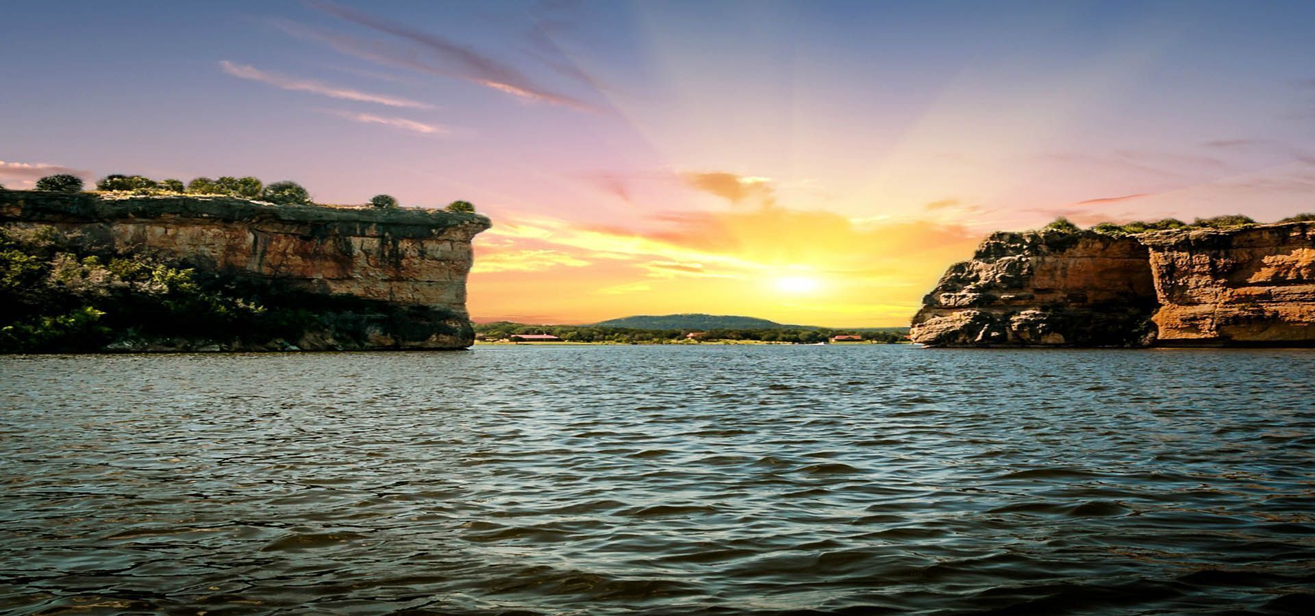 A sunset over a calm river with cliffs on either side.