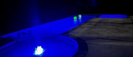 A pool area with a blue-lit water feature and a concrete deck.