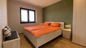 Quarto com cama, mesas de cabeceira, um guarda-roupa e uma janela.