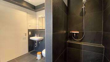 Une salle de bain moderne avec un lavabo, un miroir et une douche.