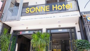 Exterior del hotel SONNE, con entrada visible, una escalera y plantas en macetas.
