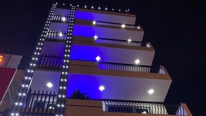Un hotel de diseño moderno, con varios balcones y un llamativo letrero iluminado.