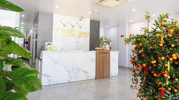 Zona de recepción de un hotel con mostrador y escritorio de mármol, y un cartel indicador.